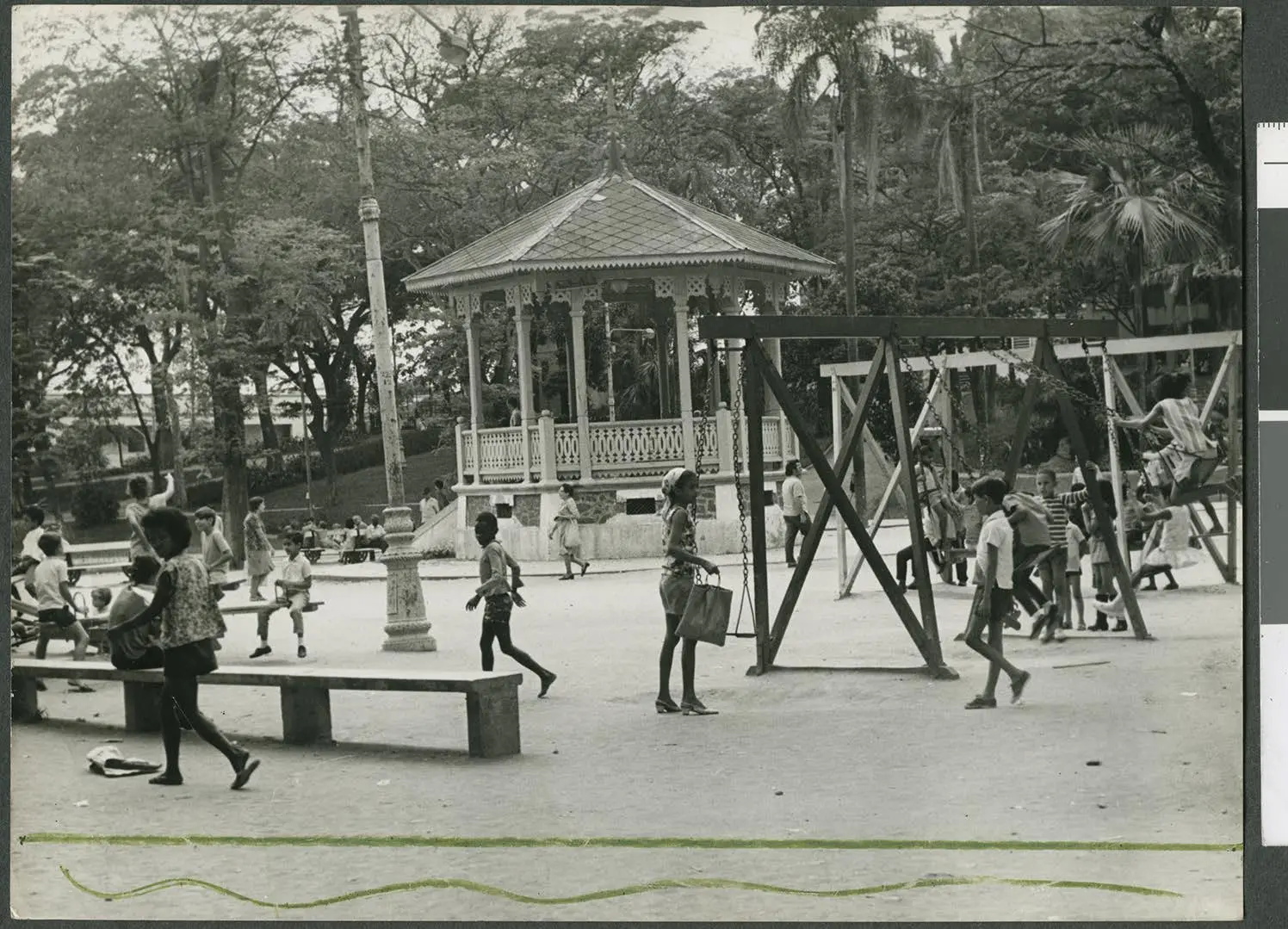 Parque com crianças brincando, bancos e balanço.