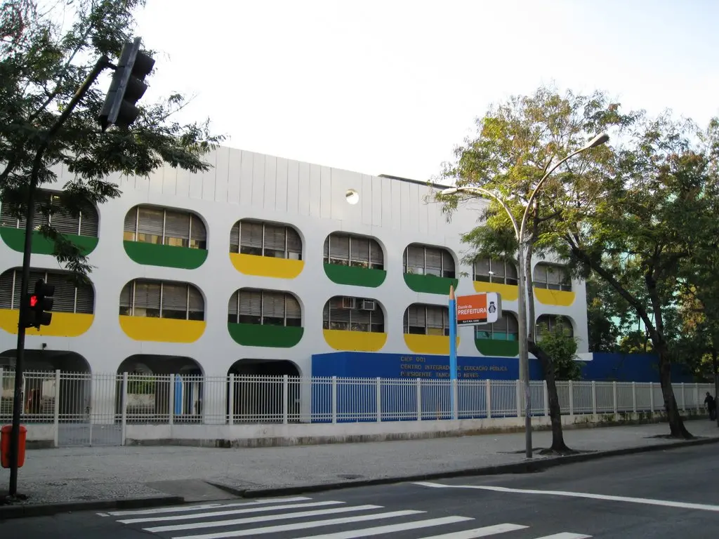 Prédio moderno com fachada branca, elementos decorativos e céu azul.