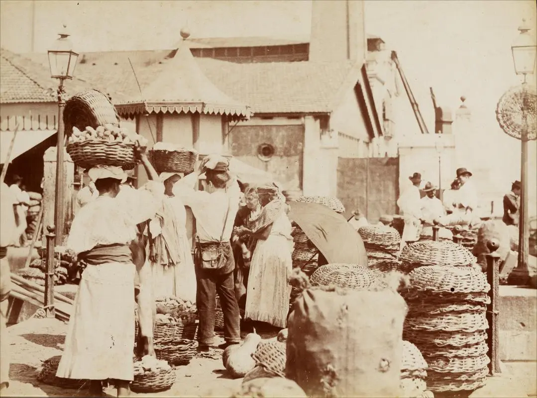 Mercado antigo com mulheres carregando cestos de frutas.