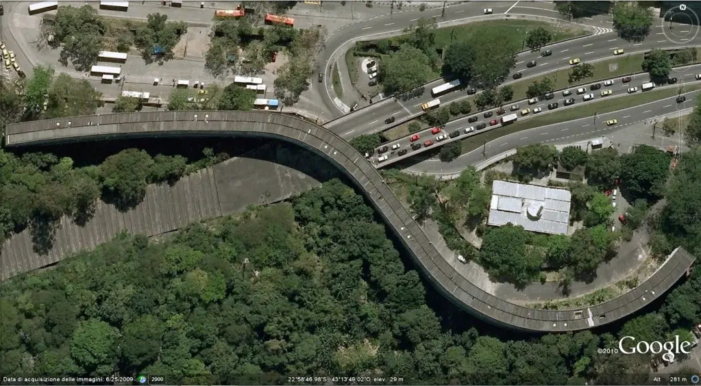 Viaduto urbano com tráfego e áreas verdes.