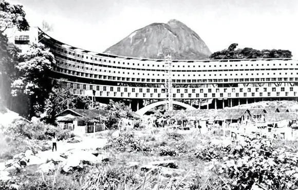 Conjunto residencial em preto e branco, com estrutura arredondada e montanha ao fundo.