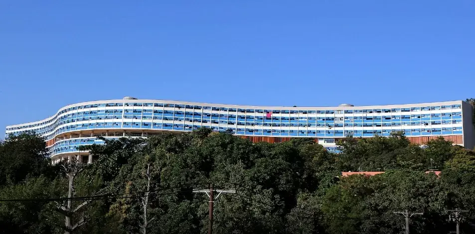 Conjunto residencial com prédio curvado e céu azul claro.