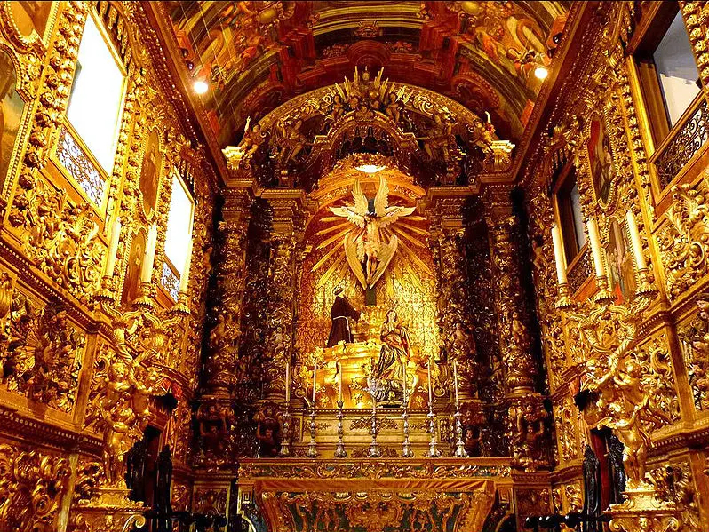 Altar ornado com detalhes dourados e esculturas religiosas.