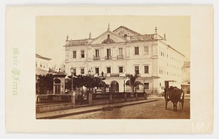 Teatro antigo com carruagem à frente.