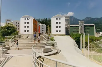Complexo habitacional com edifícios, rampas e montanha ao fundo.
