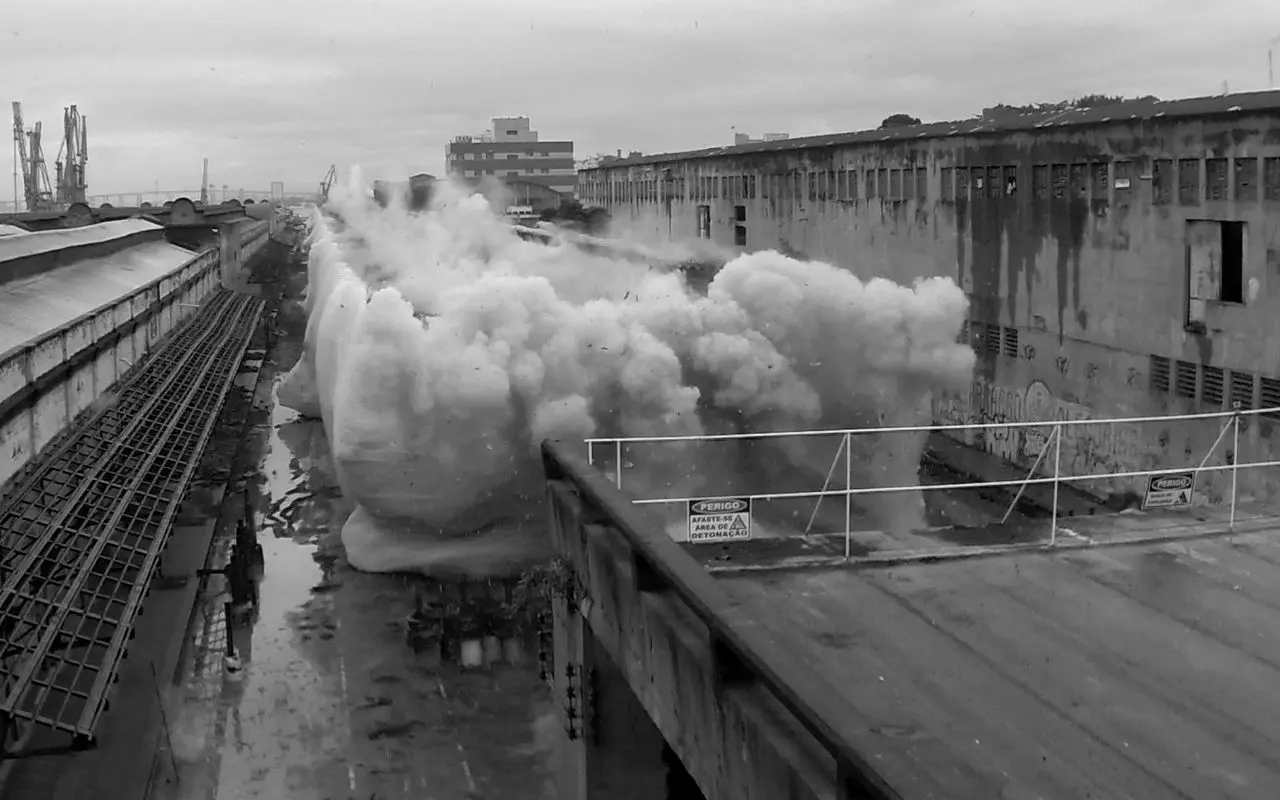 Imagem industrial com fumaça e edifícios metálicos.