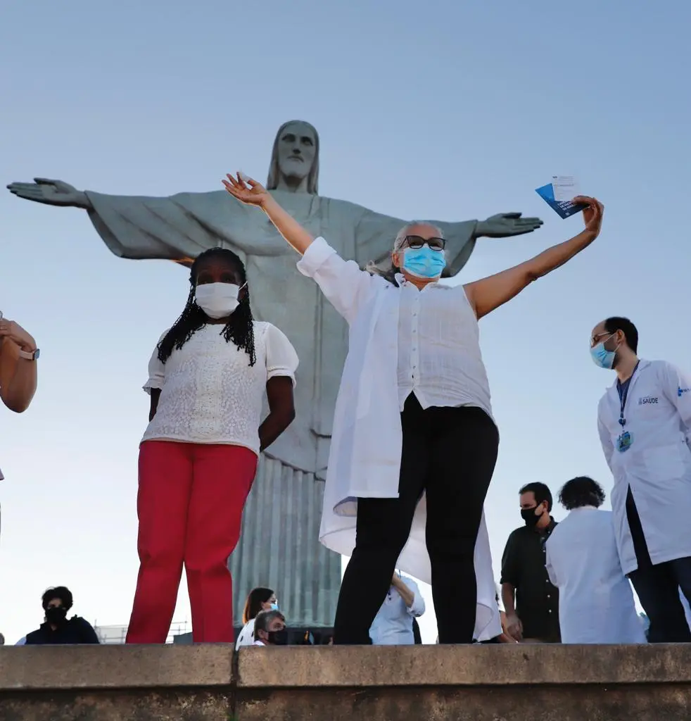 Cerimônia de vacinação com Cristo Redentor ao fundo.