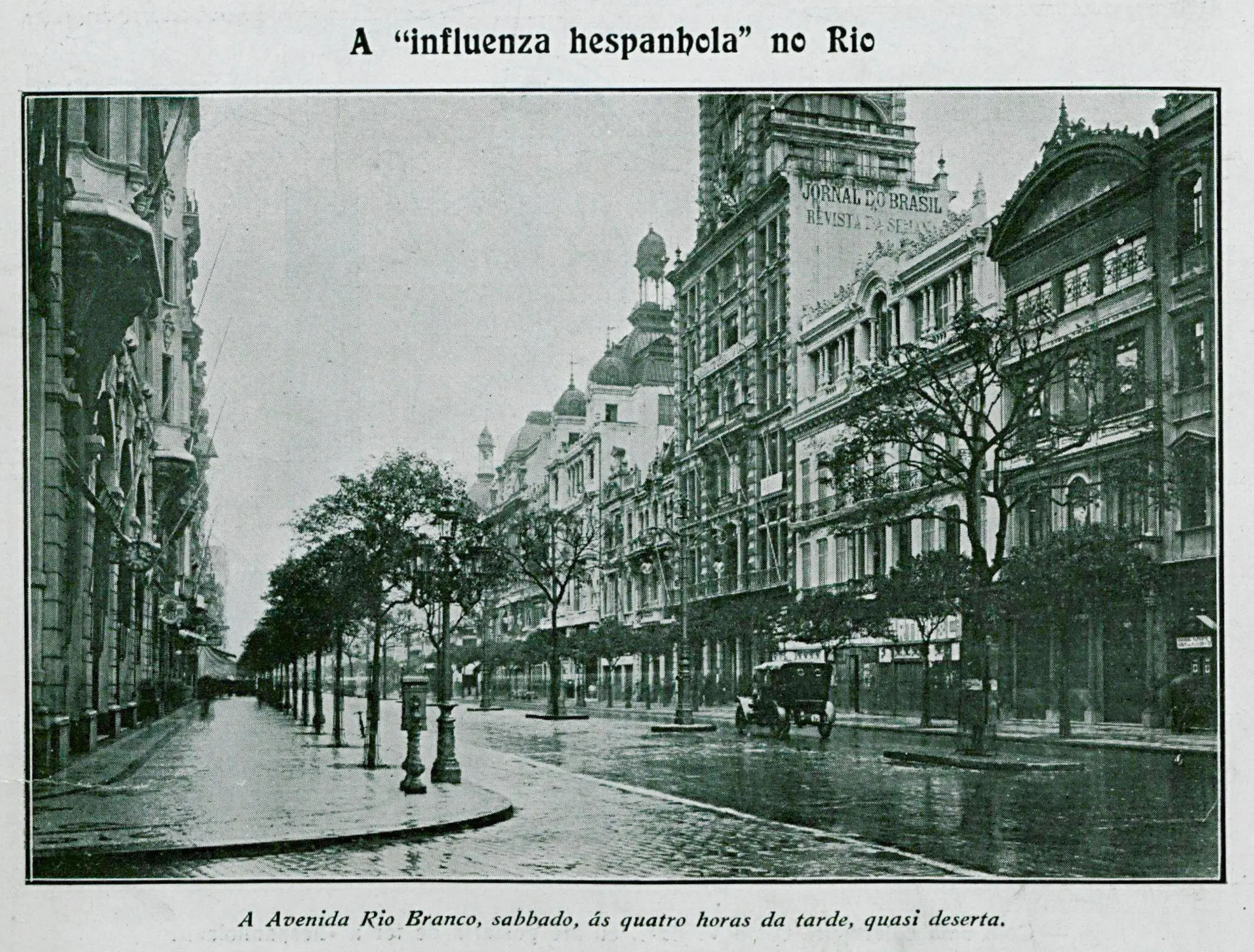 Fotografia preto e branco de avenida chuvosa com edifícios clássicos e sinal do "Jornal do Brasil".