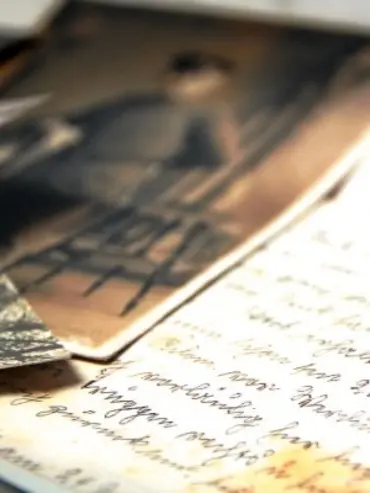 Fotografia antiga em preto e branco com pessoa sentada e papel com texto.