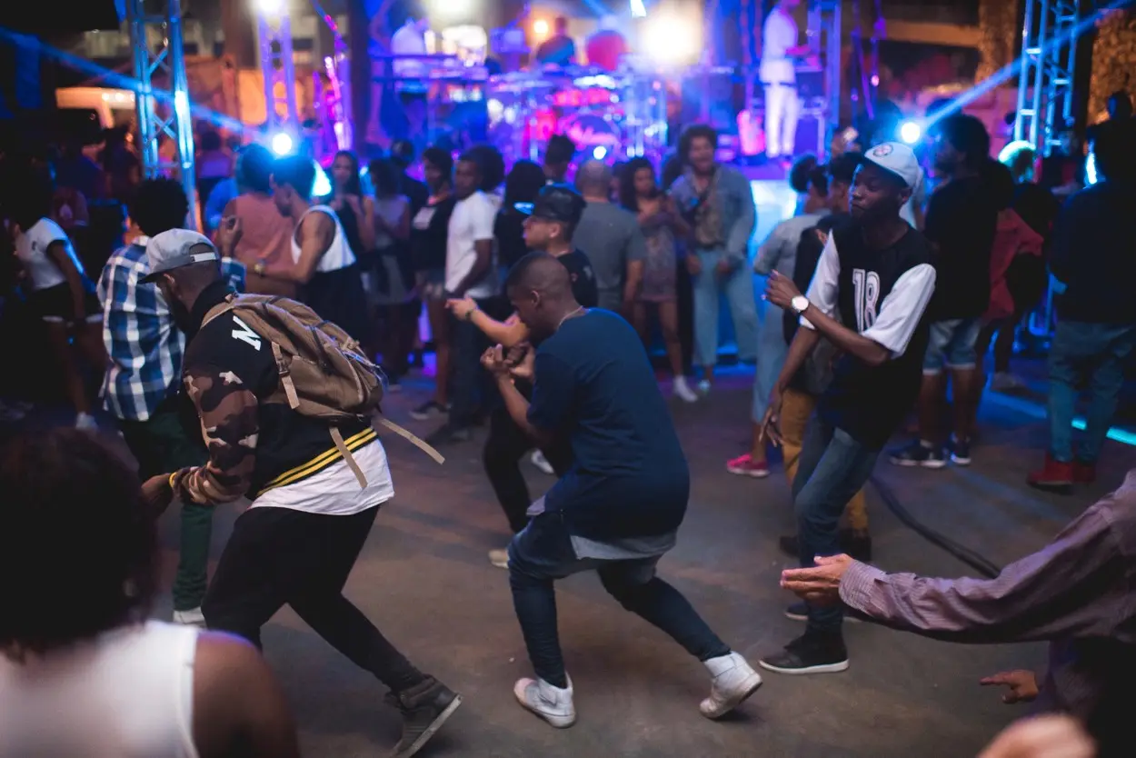 Baile noturno animado com danças e luzes coloridas.