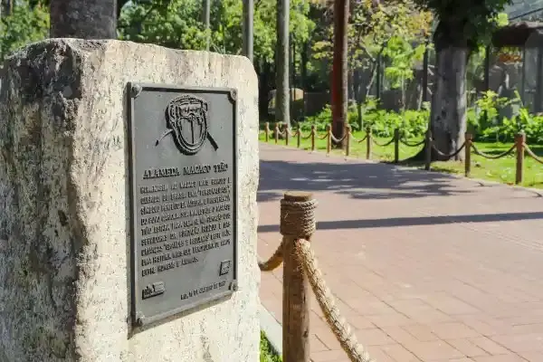 Monumento em parque com placa e caminho de tijolos vermelhos.