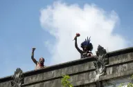 Duas pessoas erguem os braços em cenário ao ar livre.
