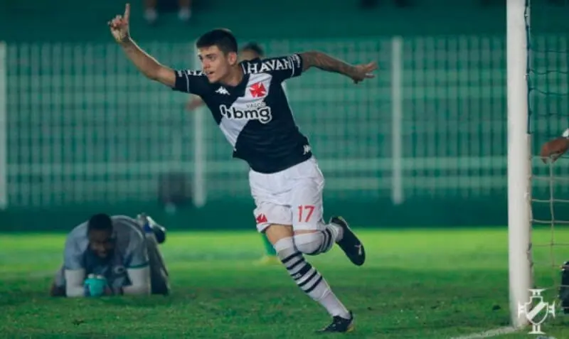 Jogador de futebol celebrando em campo verde.