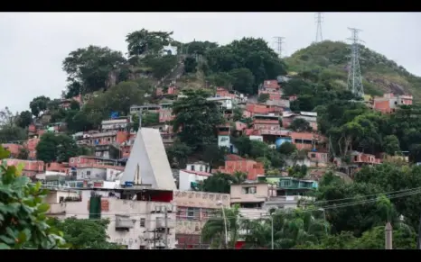 Bairro colorido em morro com casas e vegetação verde.