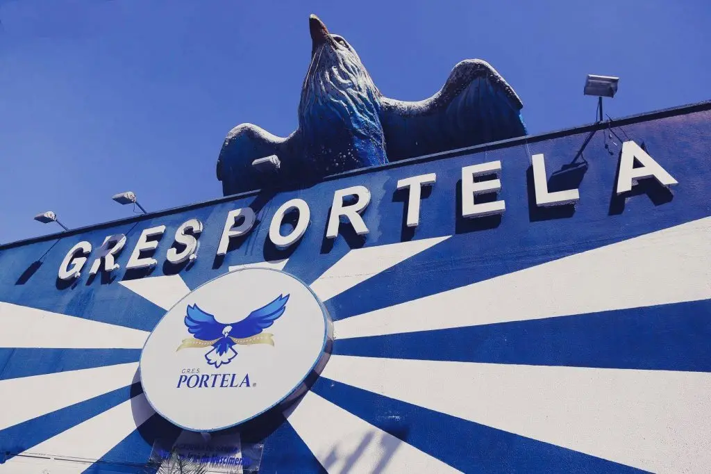 Sambódromo com placa "GRESPORTELA" e estátua de pássaro azul.