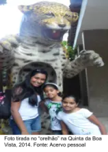 Três pessoas sorridentes em frente a estatuto de jaguar.