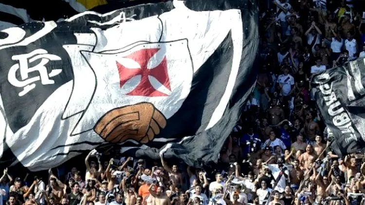 Estádio lotado durante evento esportivo com torcedores animados e bandeira do Vasco da Gama.