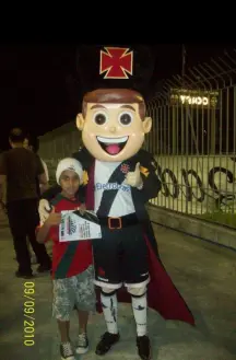 Duas pessoas posam juntos, um mascote militar segurando jornal.