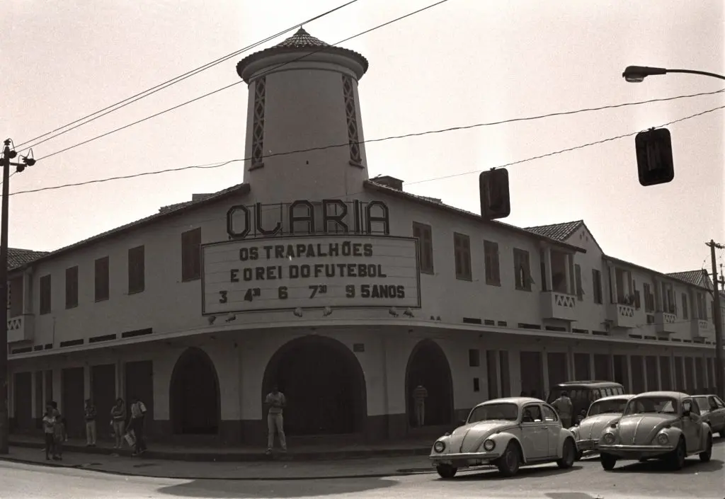 Cinema localizado em subúrbio com marquise e cartaz anunciando filme.