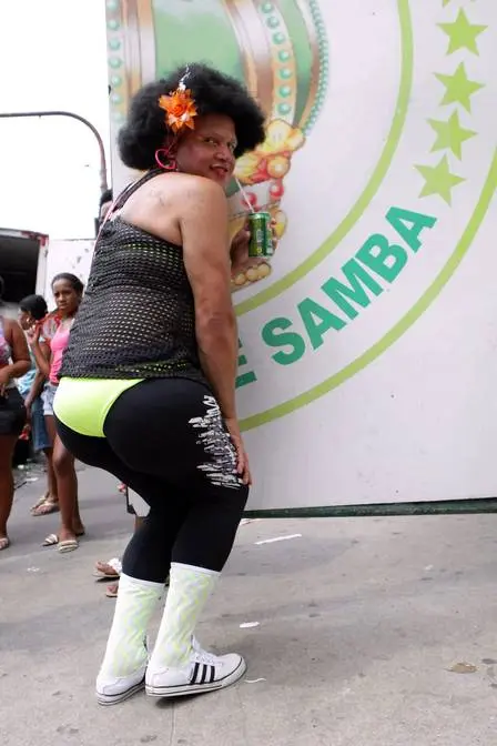 Mulher dançando samba, blusa preta, flores amarelas, caneta verde.