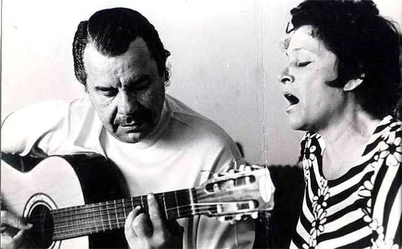 Duas pessoas tocando e cantando em preto e branco.