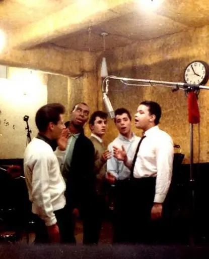 Homens em estúdio de gravação, conversando e posando.