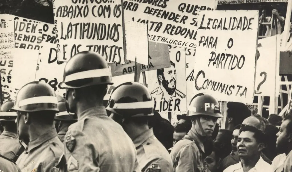 Manifestação com policiais e cartazes em preto e branco.
