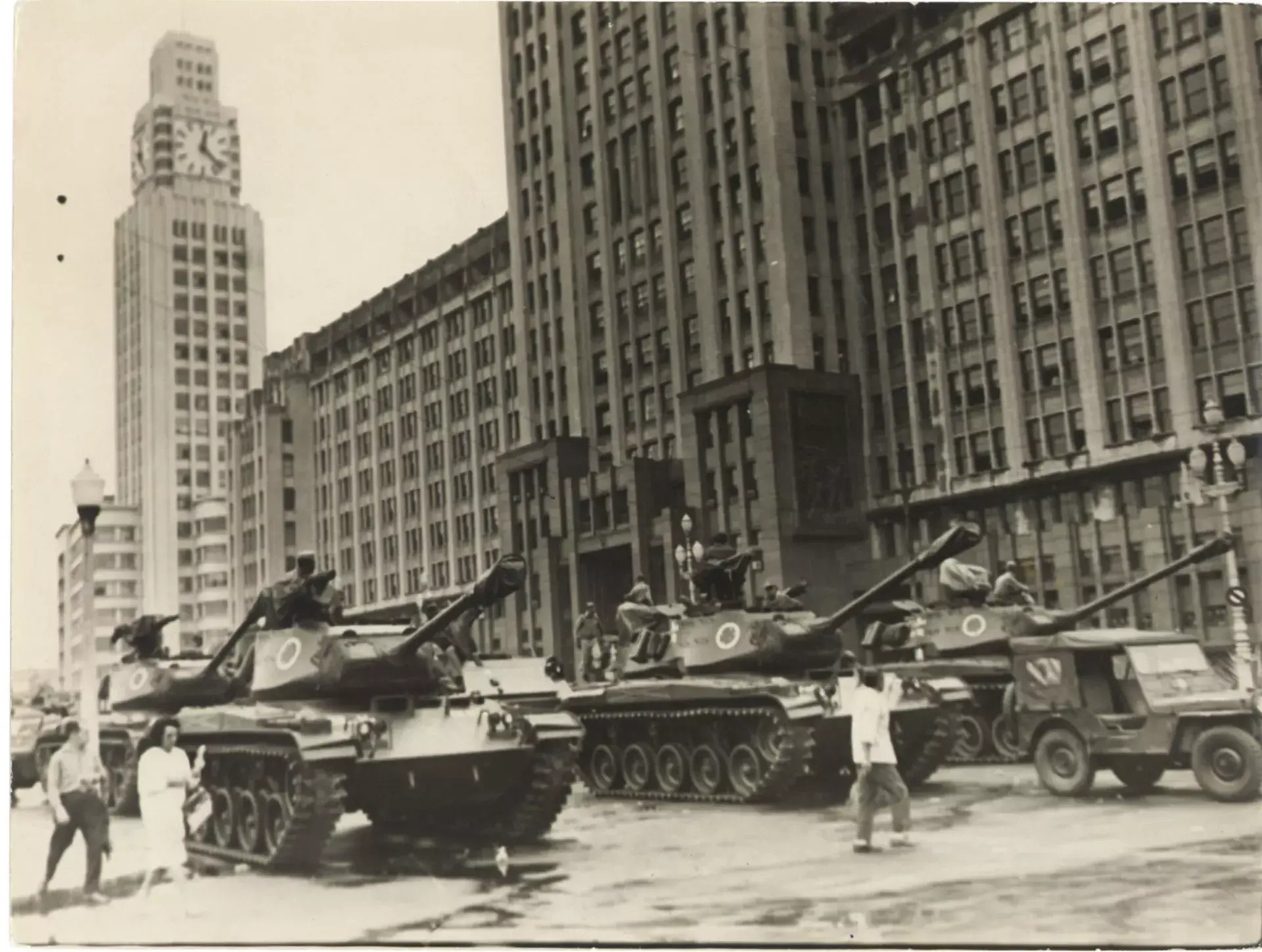 Tanques militares em frente a um grande edifício em preto e branco.