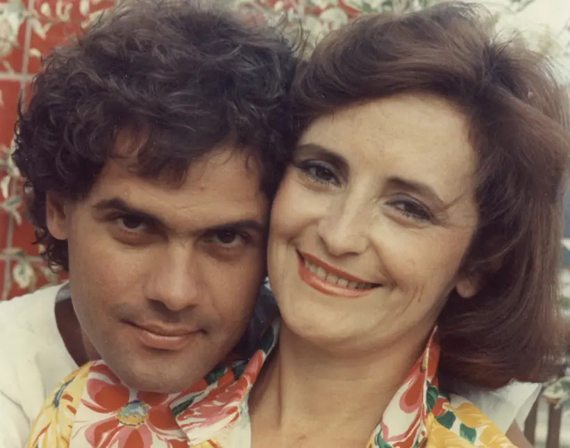 Duas pessoas sorridentes em frente a fundo floral.