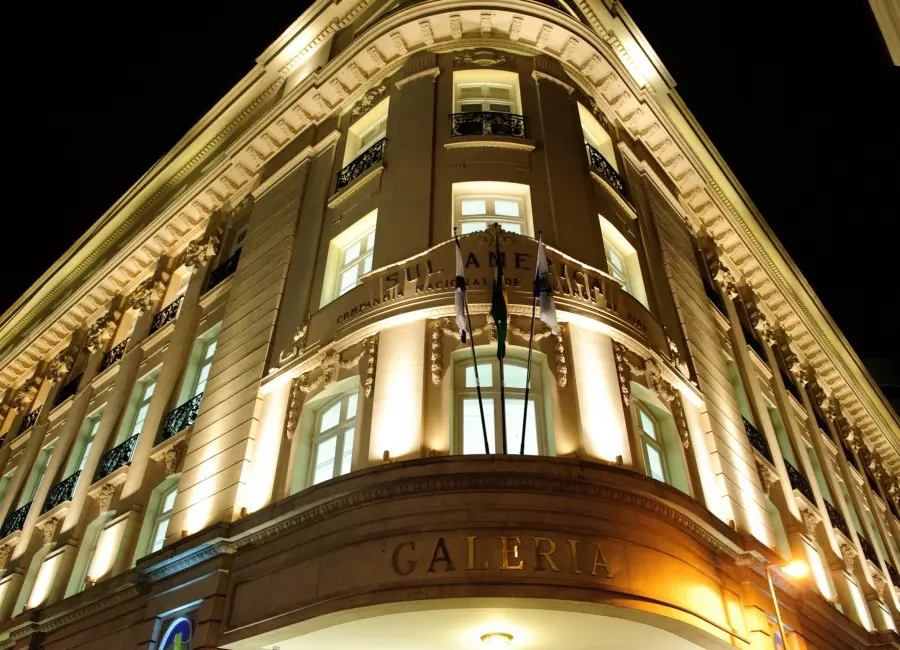 Edifício noturno com iluminação focada nas janelas e detalhes arquitetônicos.