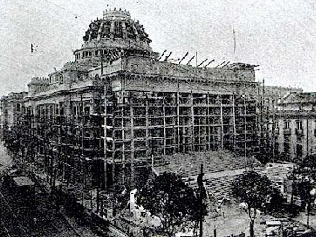 Edifício em construção com torre elevada e telhado coberto.