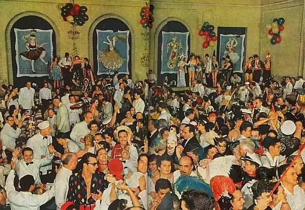 Evento social com dança e conversa em salão decorado.