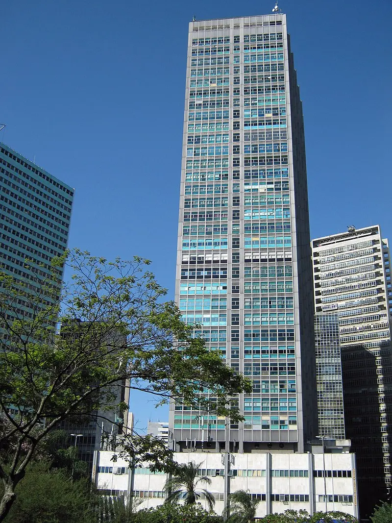 Edifícios urbanos com fachadas azuis e cinza, céu claro.