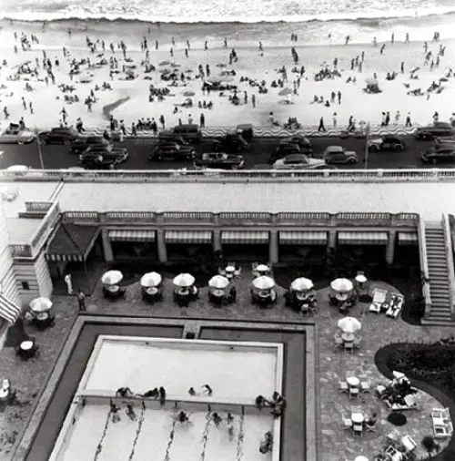 Hotel Copacabana Palace com praia lotada e piscina movimentada.
