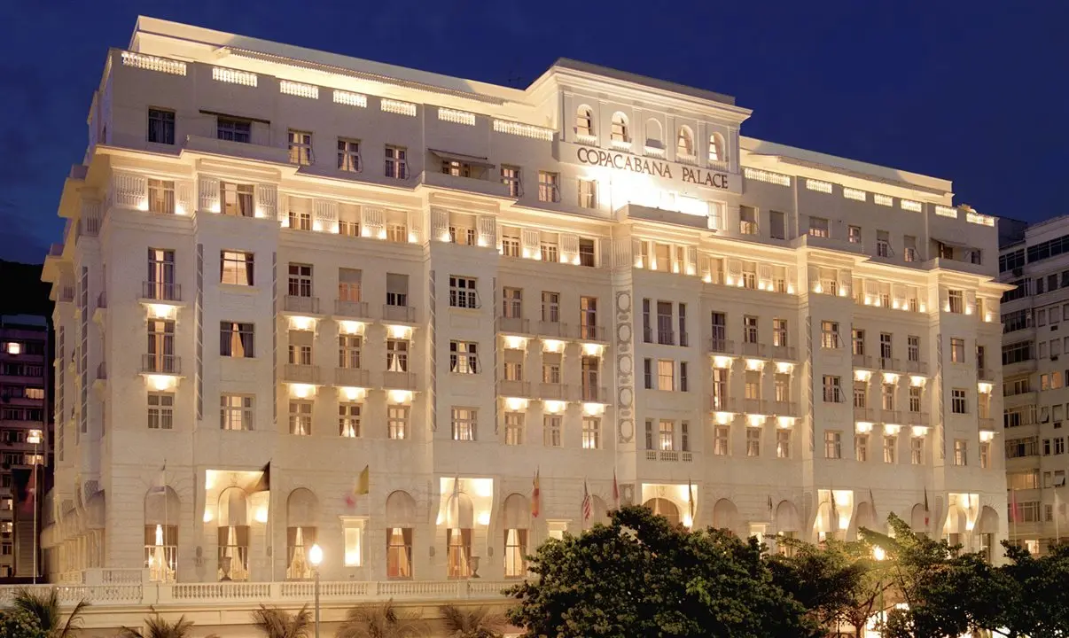 Edifício iluminado noturnamente, Copacabana Palace destacado.