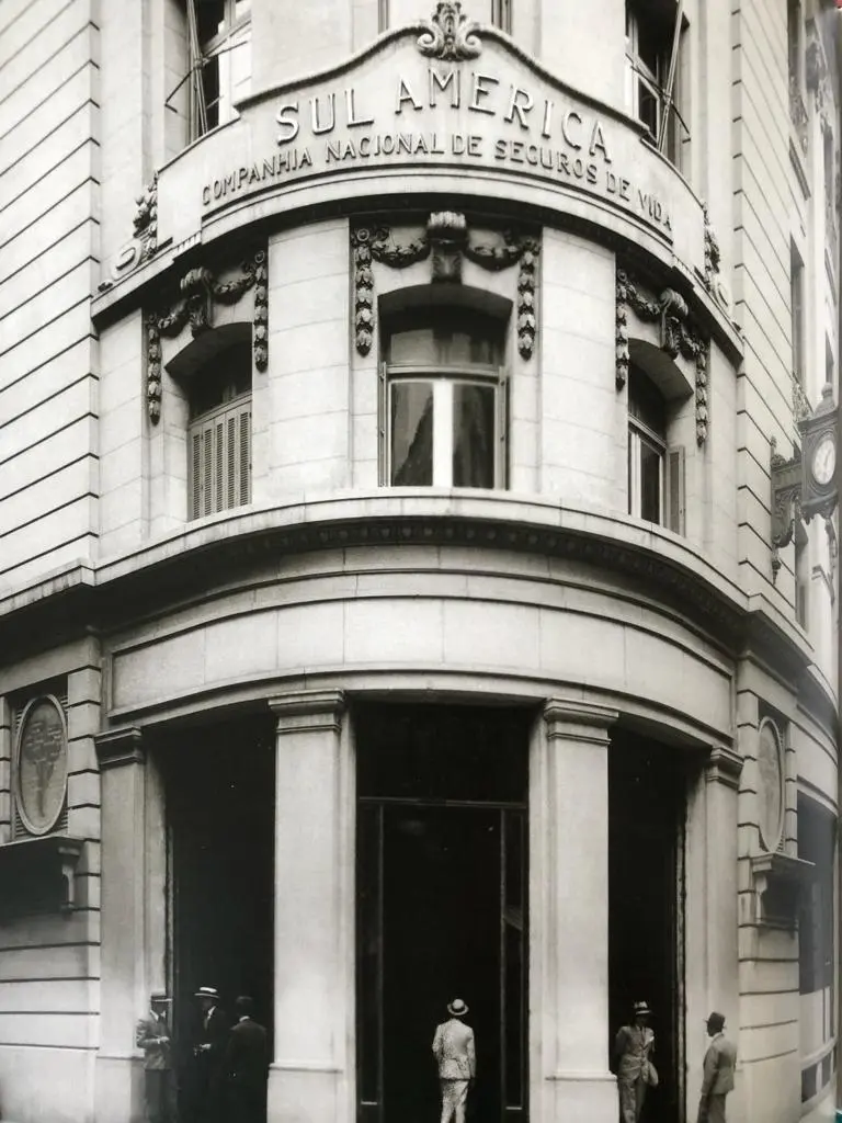 Edifício com inscrição "SUL AMÉRICA", entrada principal e torre com relógio.