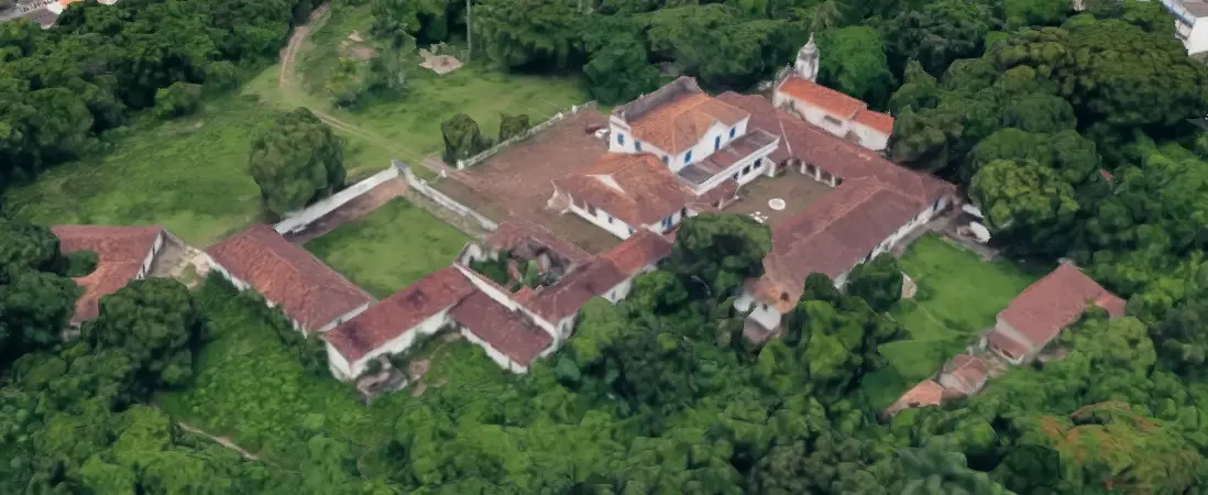 Fazenda aérea com estrutura central cercada por edificações e árvores verdes.