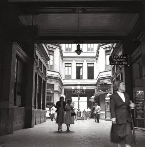 Corredor interno com pessoas caminhando, ambiente histórico.