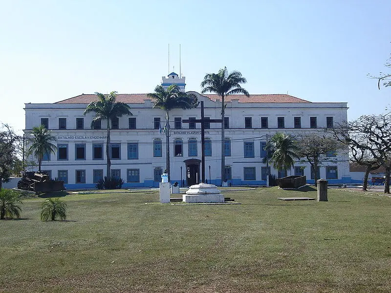 Edifício clássico com gramado verde e monumento central.