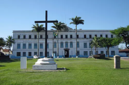 Edifício histórico com cruz monumental e árvores em Fazenda Santa Cruz.