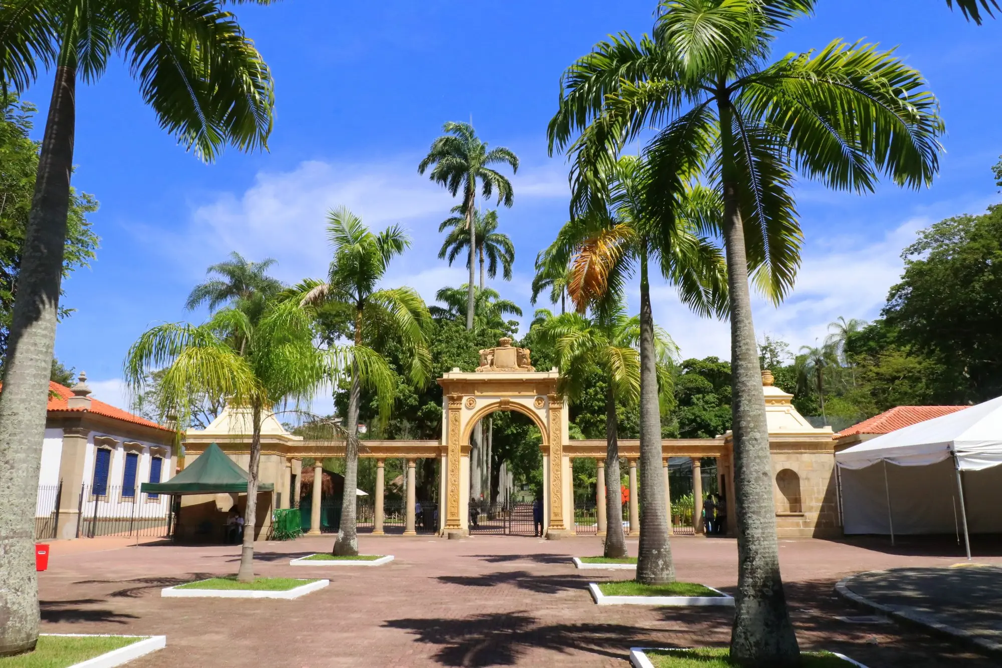 Entrada monumental de zoológico com arco amarelo e detalhes dourados.