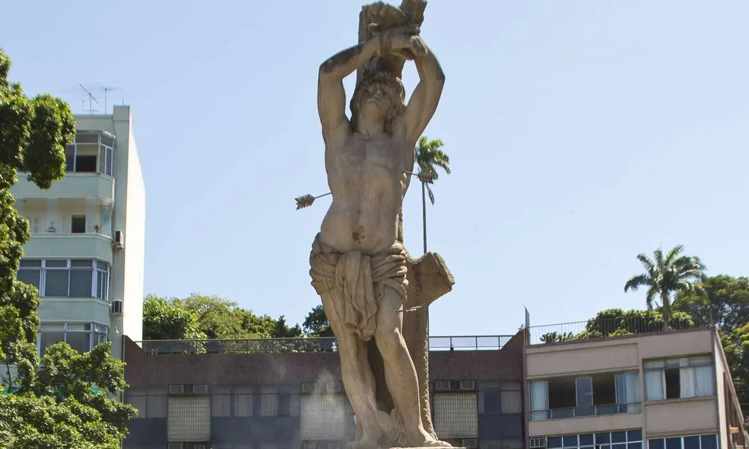 Estátua antropomórfica com arco e flecha em ambiente urbano.