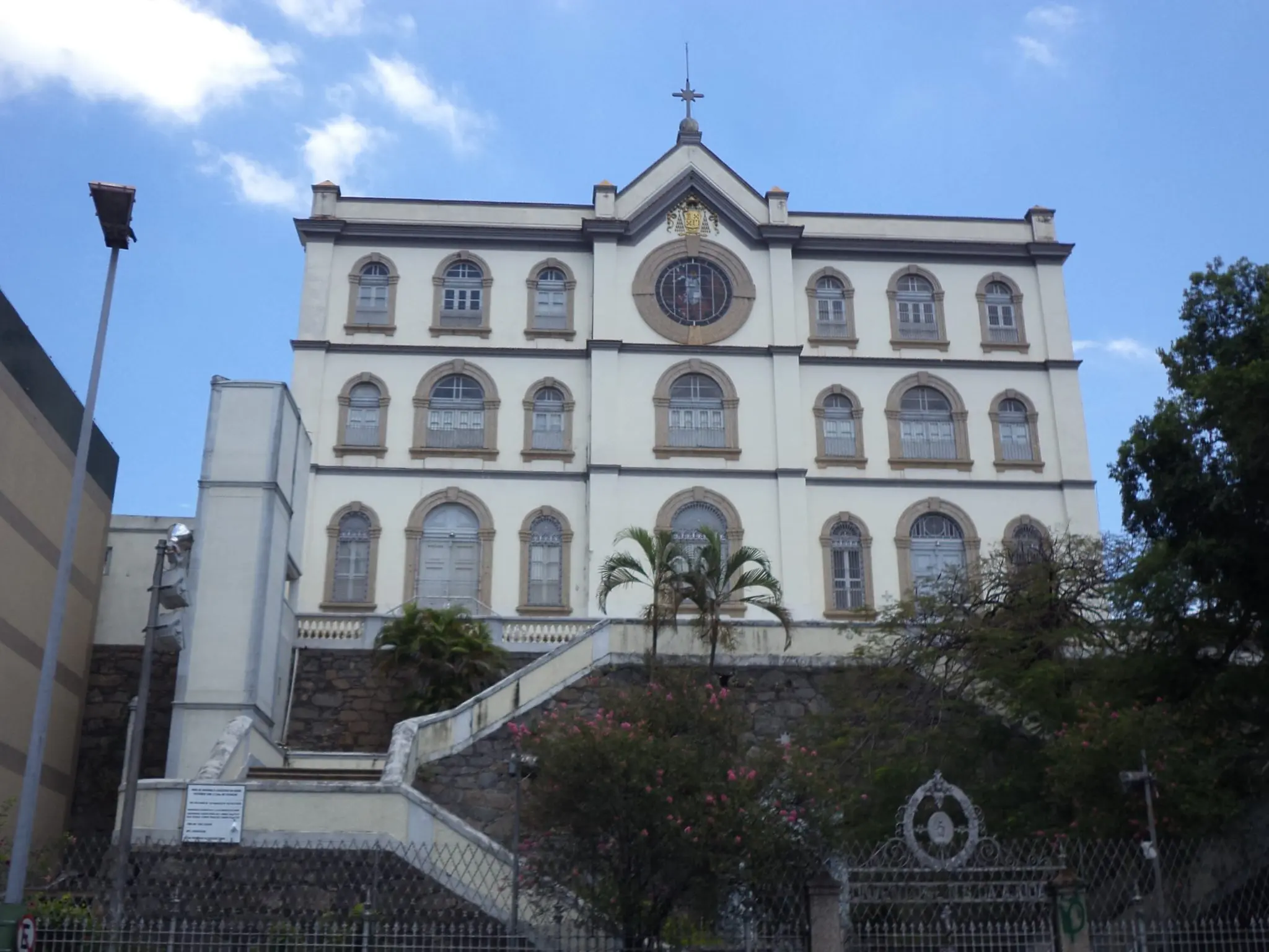 Edifício histórico Convento da Ajuda com fachada clara, janelas arredondadas e cruz metálica.