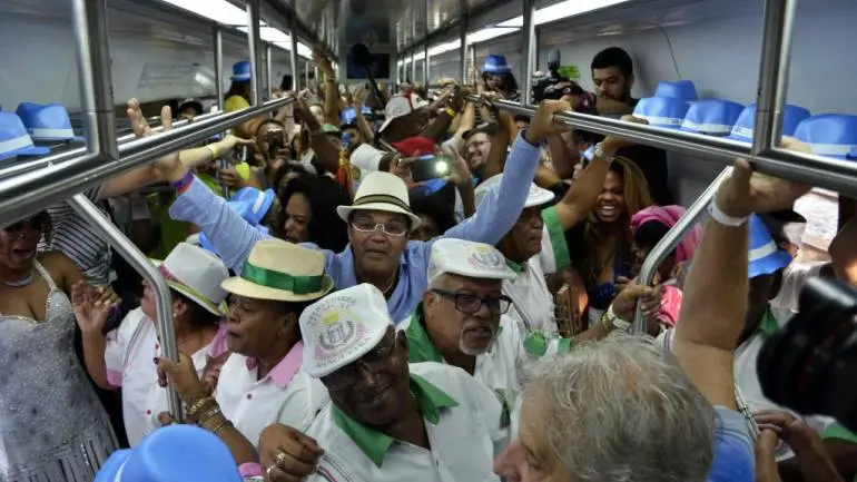 Multidão em movimento dentro de um trem, ocupando todo o espaço disponível.