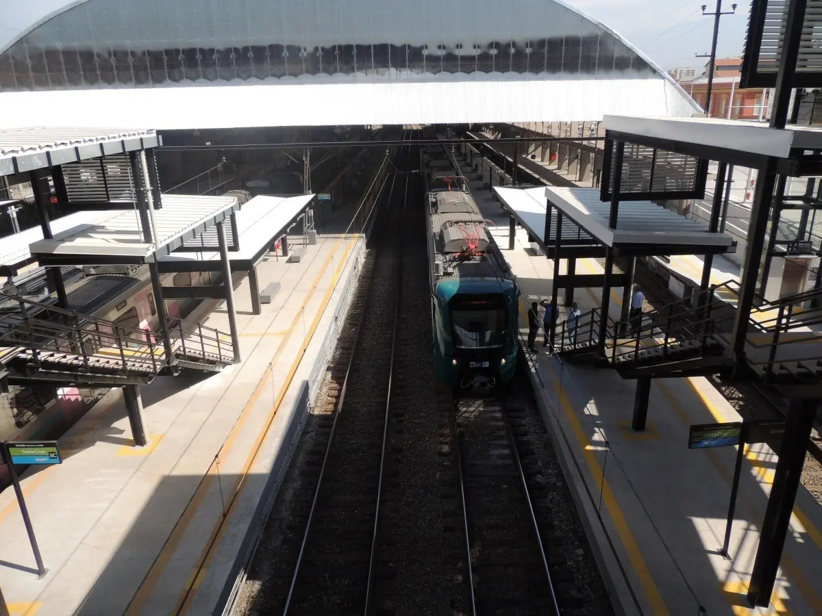 Estação ferroviária com plataformas elevadas e trem azul.