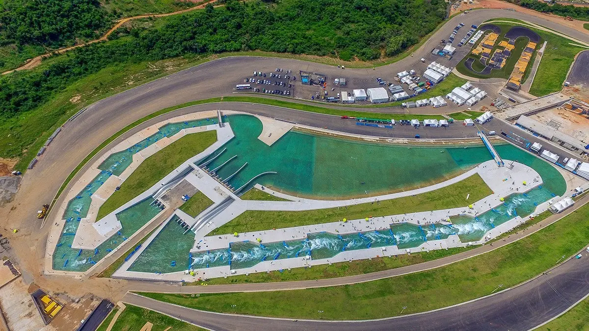 Complexo esportivo em área verde com lago e estradas.