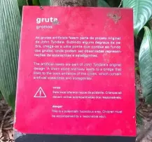 Cartaz vermelho sobre grutas com folhas verde e marrom.