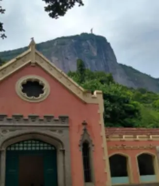 Edifício histórico com montanha ao fundo, estátua humana na rocha.