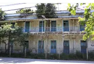 Prédio antigo com árvores e janelas quadradas.