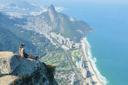 Paisagem urbana com mar e montanha verde.